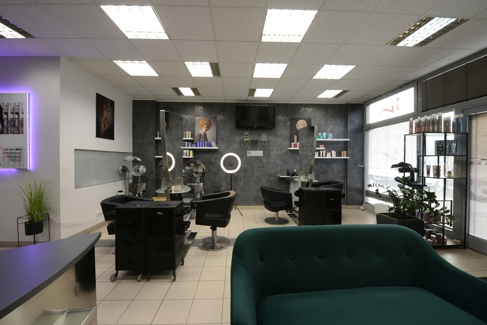 Interiér salónu In Hair Studio se smaragdovou pohovkou a kadeřnickými křesly